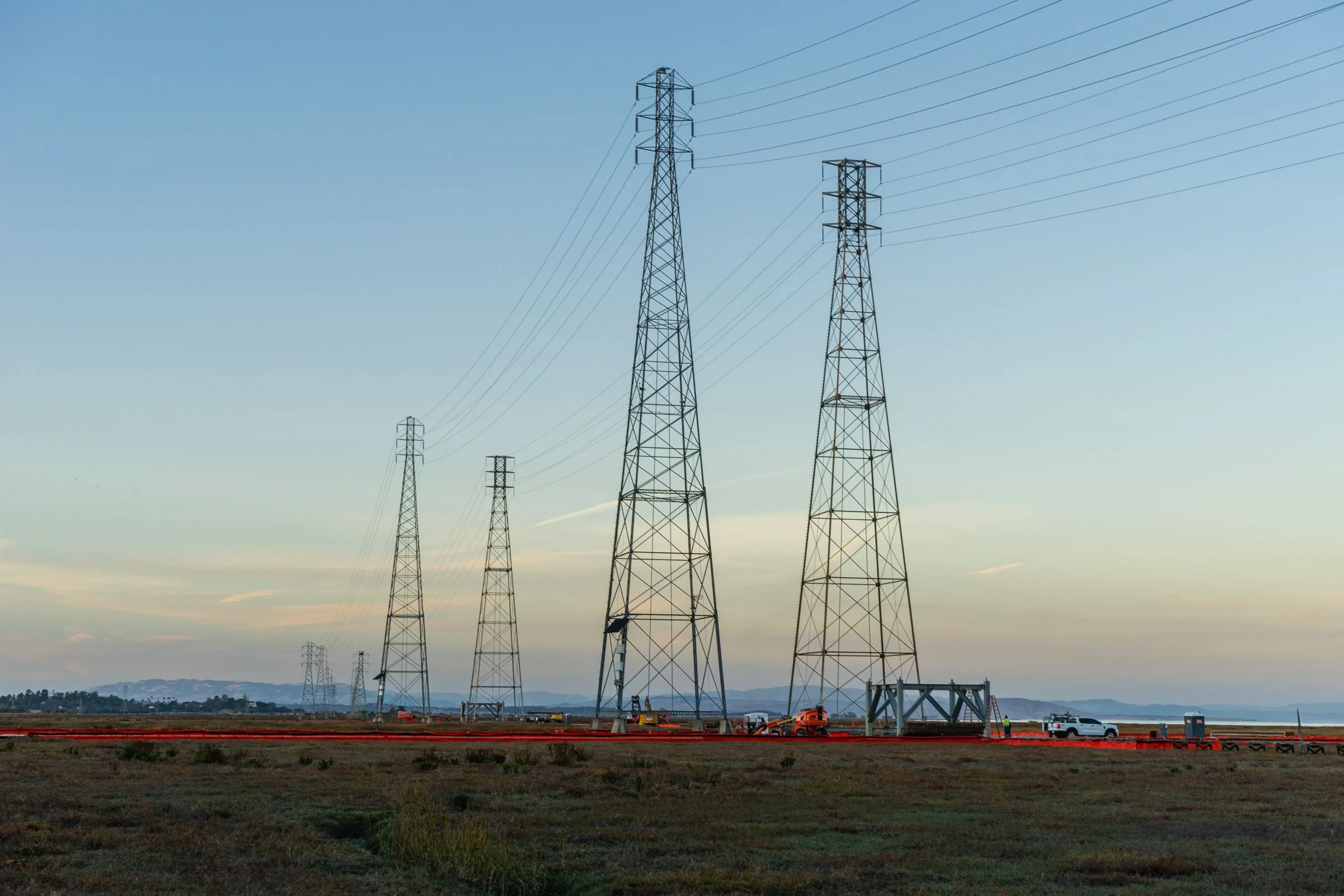 High-voltage transmission towers silhouetted against a dusk sky